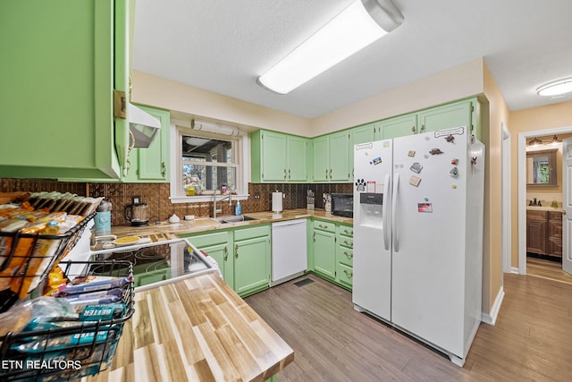 kitchen featuring tasteful backsplash, light countertops, a sink, white appliances, and green cabinetry