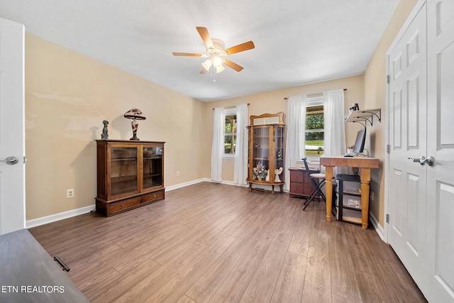 home office featuring wood finished floors, a ceiling fan, and baseboards