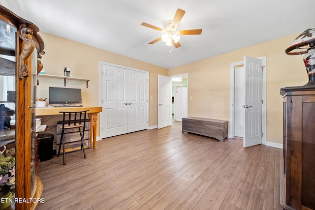 office space featuring a ceiling fan, light wood-type flooring, and baseboards