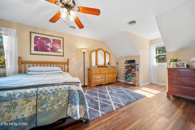 bedroom featuring visible vents, a ceiling fan, vaulted ceiling, wood finished floors, and baseboards