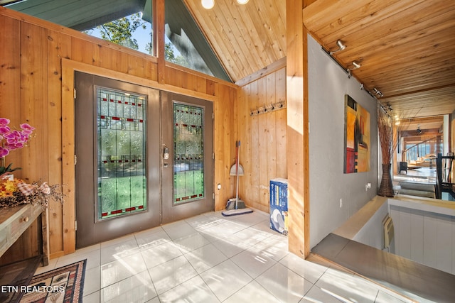 tiled entrance foyer featuring french doors, high vaulted ceiling, wooden ceiling, and wooden walls