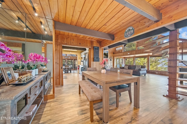 dining area with light hardwood / wood-style flooring, beam ceiling, track lighting, and plenty of natural light