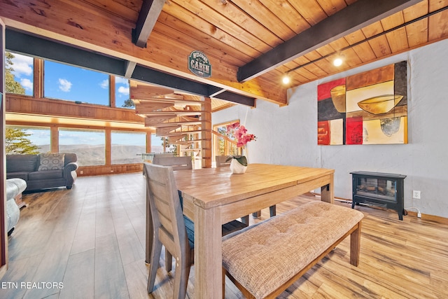 dining area with wood ceiling, a healthy amount of sunlight, a wood stove, and hardwood / wood-style floors