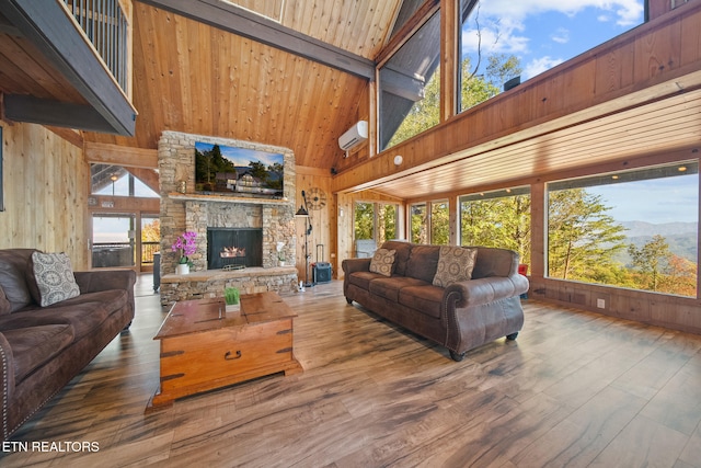 living room featuring wood walls, wood-type flooring, a stone fireplace, a mountain view, and high vaulted ceiling