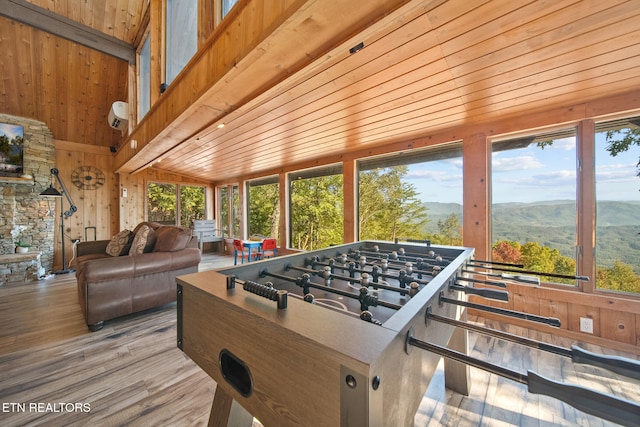 recreation room featuring wood walls, light wood-type flooring, wooden ceiling, vaulted ceiling, and a mountain view