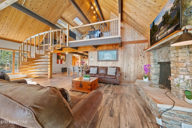 living room featuring a stone fireplace, hardwood / wood-style flooring, high vaulted ceiling, and wooden ceiling