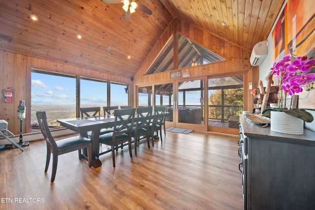 dining room with a wealth of natural light, an AC wall unit, light wood-type flooring, and high vaulted ceiling