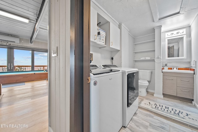 laundry area with sink, washer and dryer, and light hardwood / wood-style flooring