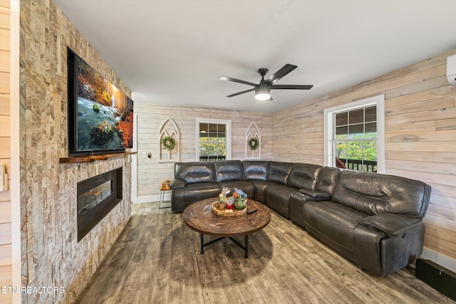 living room with ceiling fan, wooden walls, plenty of natural light, and hardwood / wood-style floors