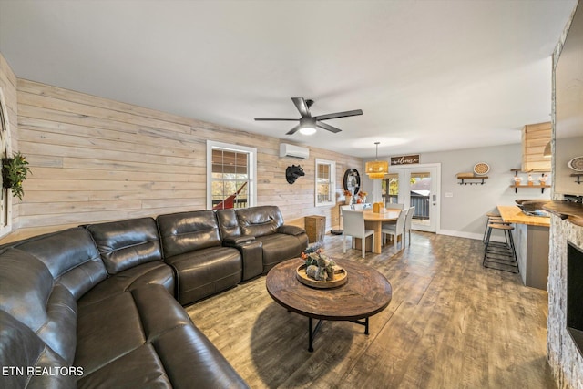 living room with a healthy amount of sunlight, wood walls, wood-type flooring, and a wall mounted air conditioner