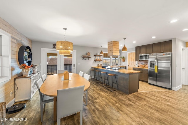 dining space featuring light hardwood / wood-style flooring, wood walls, and a notable chandelier