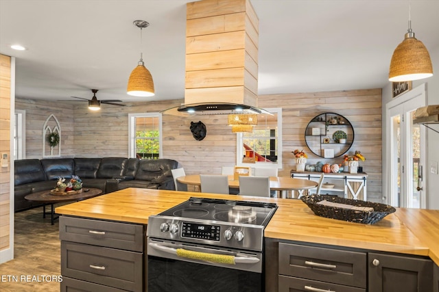 kitchen featuring wood counters, hanging light fixtures, wooden walls, and electric range