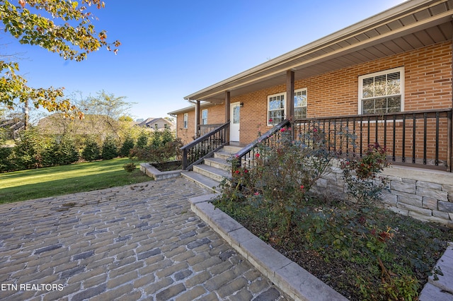 exterior space featuring a yard, a patio, and brick siding