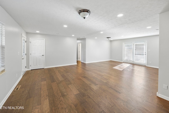 spare room with a textured ceiling, baseboards, wood finished floors, and recessed lighting