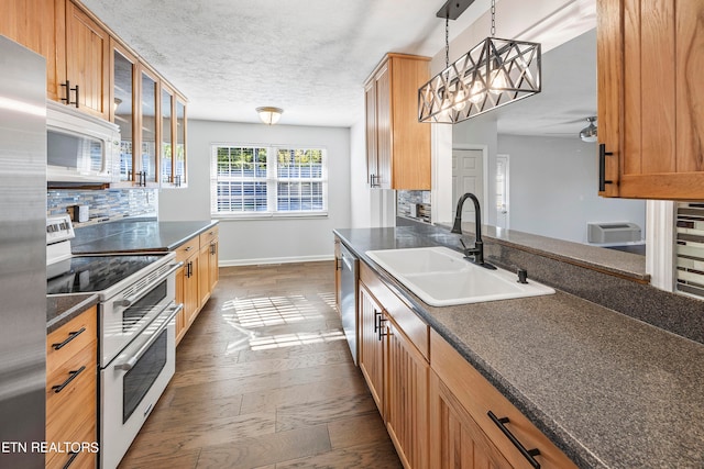 kitchen with stainless steel appliances, dark countertops, a sink, and backsplash