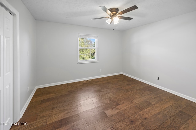 empty room featuring a textured ceiling, baseboards, dark wood finished floors, and a ceiling fan