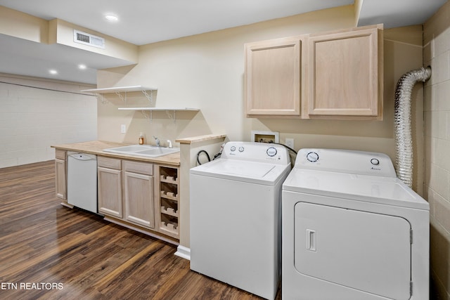 clothes washing area featuring sink, washer and clothes dryer, and dark hardwood / wood-style floors