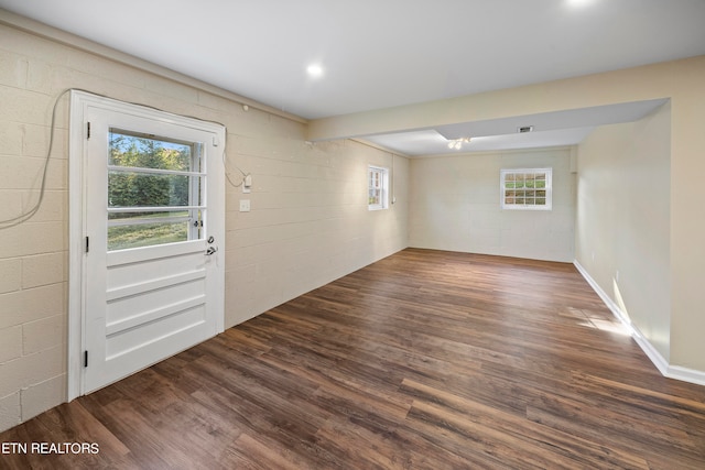 empty room featuring a wealth of natural light, concrete block wall, recessed lighting, and wood finished floors