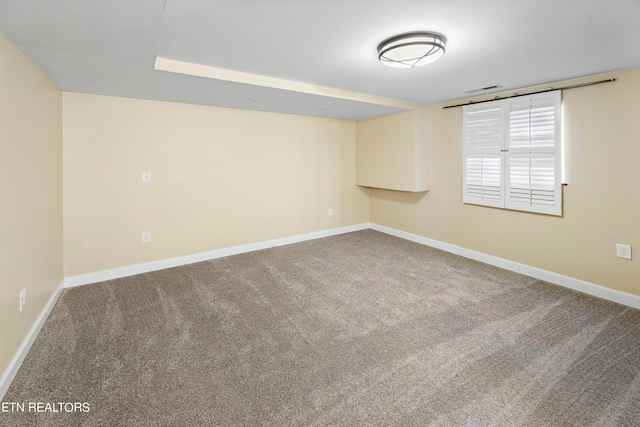 spare room with carpet floors, visible vents, and baseboards