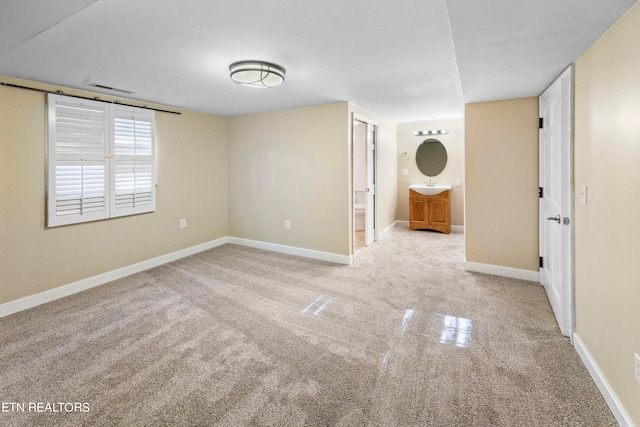 carpeted spare room with visible vents, a sink, and baseboards