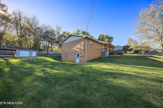 view of side of property with brick siding, a lawn, an outdoor structure, and fence