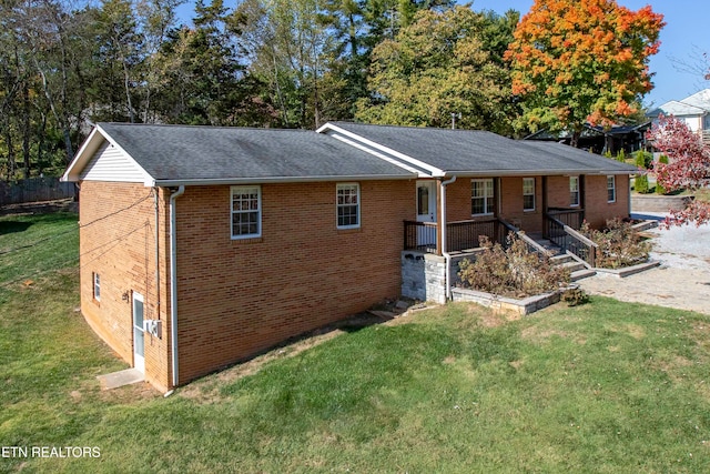 single story home featuring a shingled roof, a front yard, and brick siding