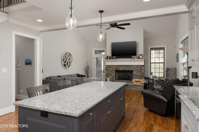 kitchen featuring light stone countertops, a fireplace, white cabinetry, ceiling fan, and dark wood-type flooring