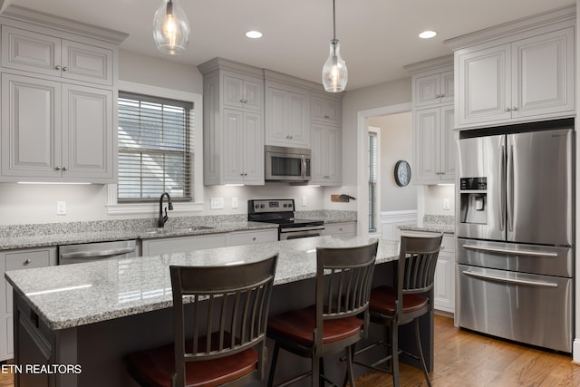 kitchen featuring a kitchen island, a kitchen breakfast bar, sink, pendant lighting, and stainless steel appliances