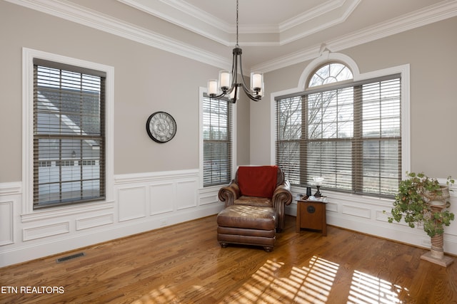 living area with ornamental molding, a notable chandelier, hardwood / wood-style flooring, and plenty of natural light