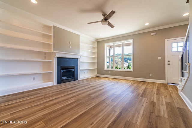 unfurnished living room with ornamental molding, hardwood / wood-style flooring, built in features, and ceiling fan