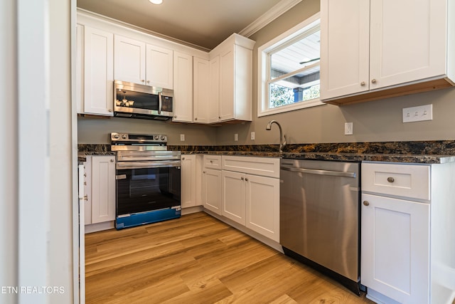 kitchen featuring appliances with stainless steel finishes, white cabinetry, light wood-type flooring, and ornamental molding