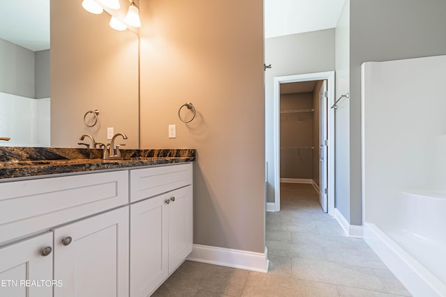 full bathroom featuring a walk in closet, vanity, walk in shower, baseboards, and tile patterned flooring