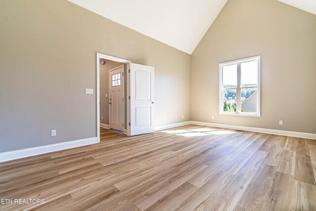 unfurnished room featuring high vaulted ceiling, baseboards, and light wood-style floors