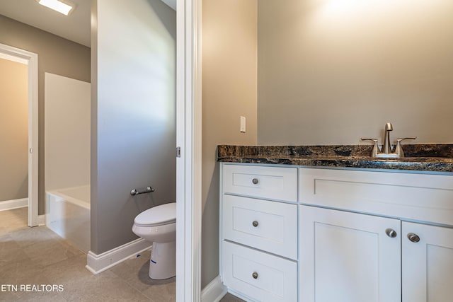 bathroom with toilet, a tub, vanity, and tile patterned flooring