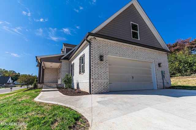 view of side of property with brick siding, driveway, and a garage