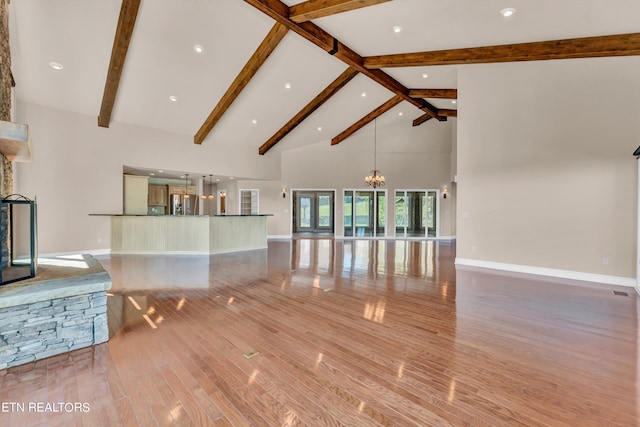 unfurnished living room featuring an inviting chandelier, beamed ceiling, high vaulted ceiling, and light wood-type flooring