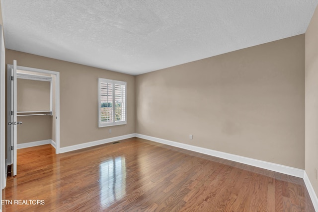 3909 Logans Landing Cir, Louisville, TN 37777 - unfurnished bedroom with wood finished floors, a closet, baseboards, a spacious closet, and a textured ceiling