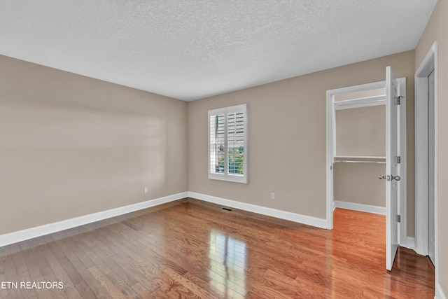 3909 Logans Landing Cir, Louisville, TN 37777 - unfurnished bedroom featuring a textured ceiling, a closet, wood finished floors, and baseboards