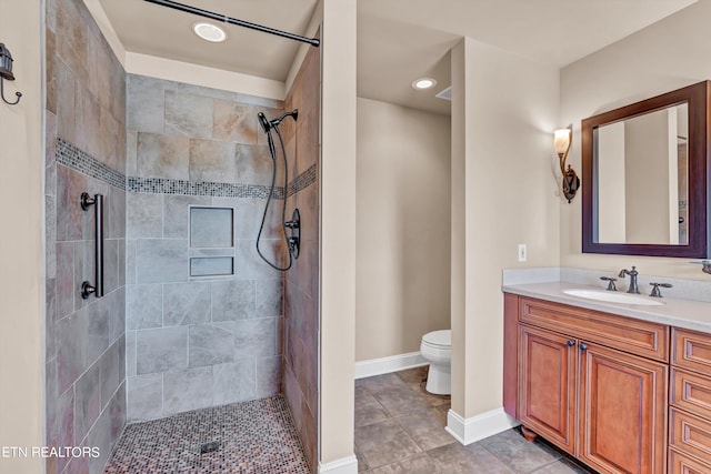 bathroom featuring toilet, tile patterned flooring, vanity, and tiled shower