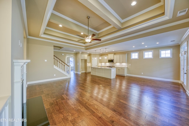 unfurnished living room with ceiling fan, ornamental molding, a tray ceiling, and hardwood / wood-style floors