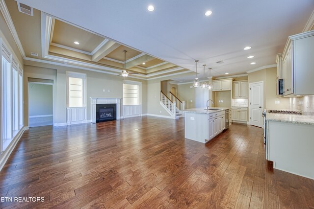 kitchen with an island with sink, dark hardwood / wood-style floors, sink, crown molding, and decorative light fixtures