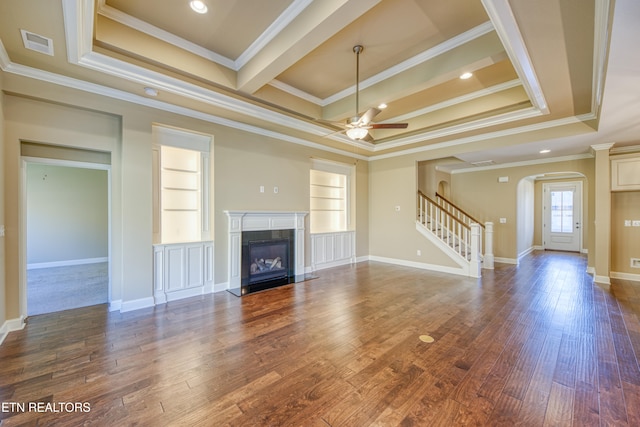 unfurnished living room featuring dark hardwood / wood-style flooring, ornamental molding, built in features, and a raised ceiling