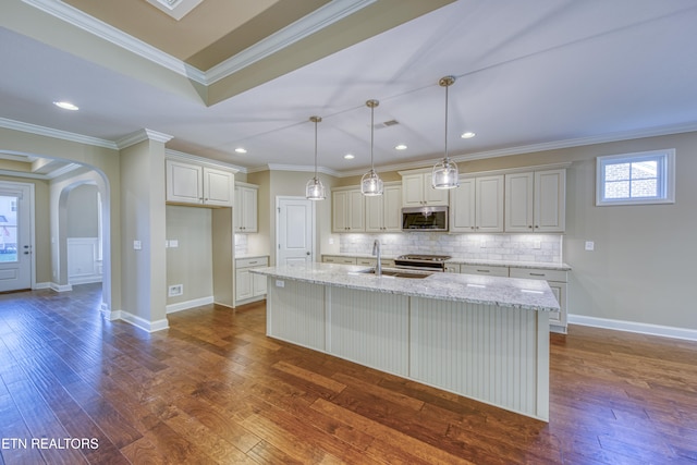 kitchen featuring an island with sink, ornamental molding, sink, appliances with stainless steel finishes, and dark hardwood / wood-style flooring