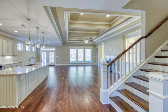 kitchen featuring sink, backsplash, light stone counters, dark wood-type flooring, and crown molding