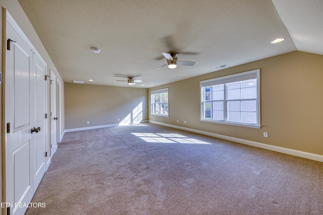 spare room with ceiling fan, lofted ceiling, and light colored carpet