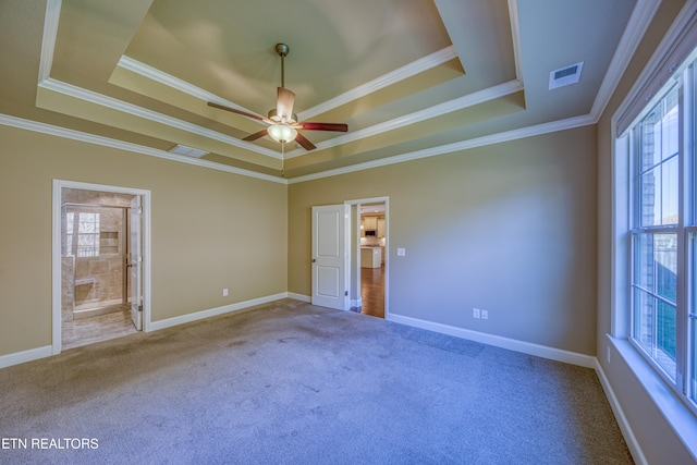 carpeted spare room featuring crown molding, a healthy amount of sunlight, a raised ceiling, and ceiling fan