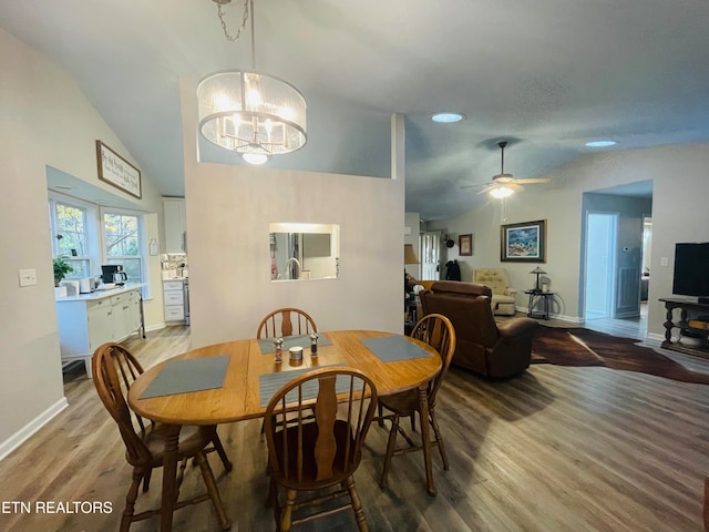 dining room featuring lofted ceiling, ceiling fan with notable chandelier, and hardwood / wood-style flooring