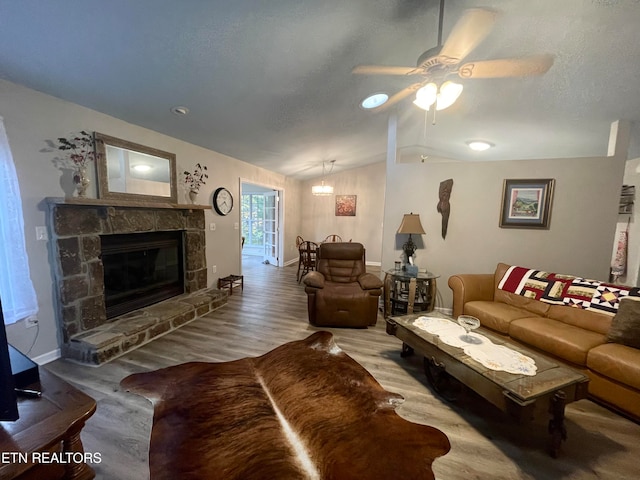 living room with lofted ceiling, light wood-type flooring, a fireplace, and ceiling fan