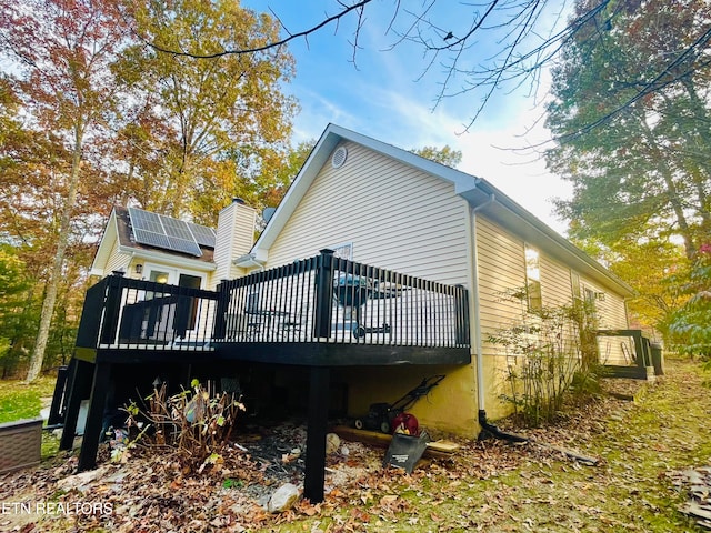 view of property exterior with a wooden deck and solar panels