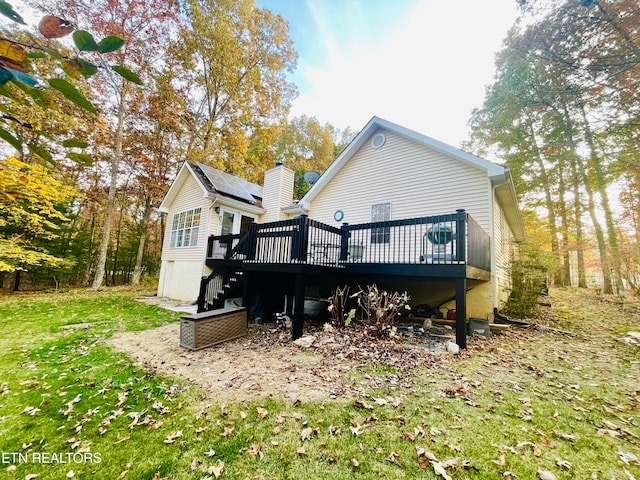 back of house featuring a yard, solar panels, and a wooden deck